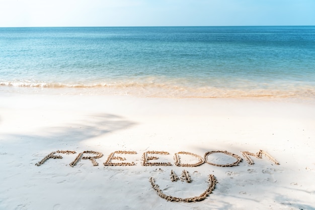 Photo the word freedom written in the sand on a tropical beach, lifestyle vacation and travel design concept