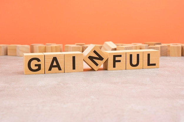 Word GAINFUL made with wood blocks orange background