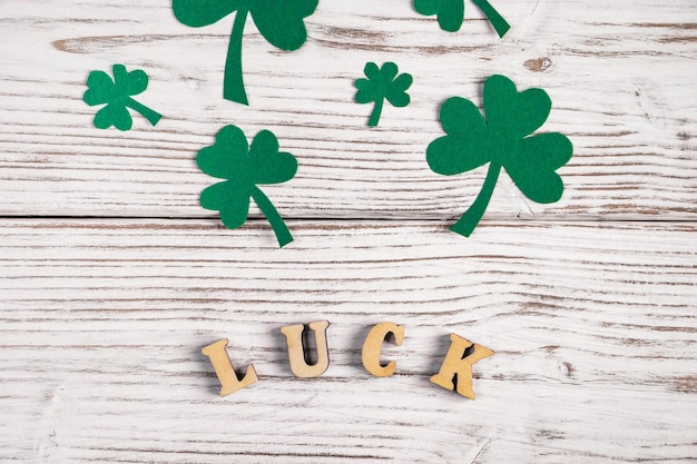 Word geluk en klaverblaadjes op een witte houten achtergrond Happy St Patrick's Day