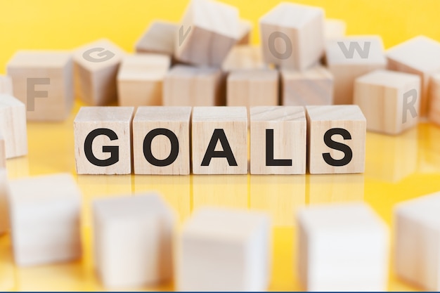 La scritta goals è scritta su una struttura a cubetti di legno. blocchi su uno sfondo giallo brillante. può essere utilizzato per affari, istruzione, concetto finanziario. messa a fuoco selettiva.