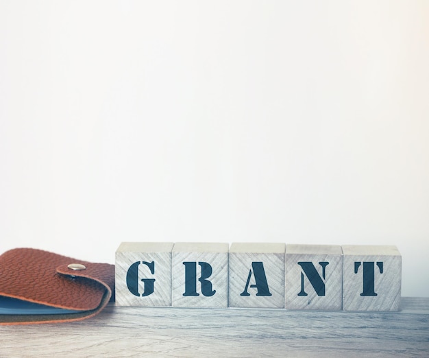 The word GRANT on building blocks and brown leather wallet Business financing concept