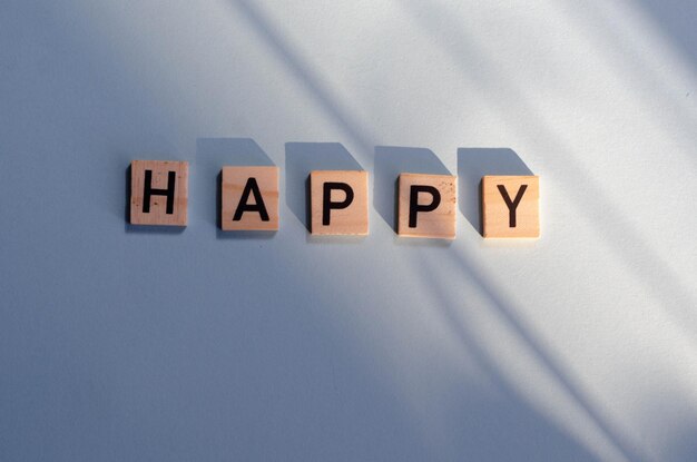 The word HAPPY, written in black letters on wooden blocks, lay flat.