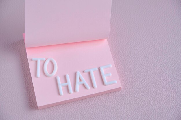 Word hate laid out white letters pink piece paperConcept hatred anger and denial