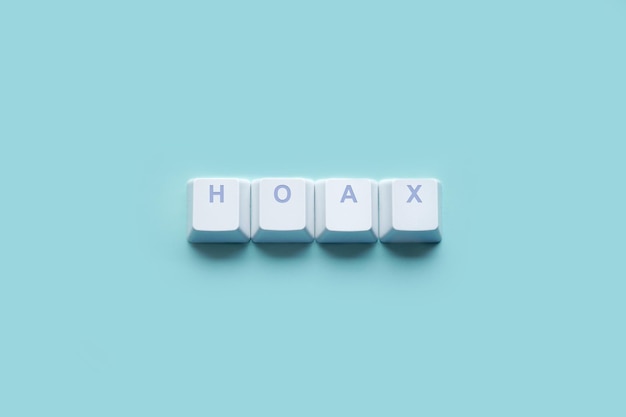 Word HOAX written on computer keyboard keys isolated on a turquoise