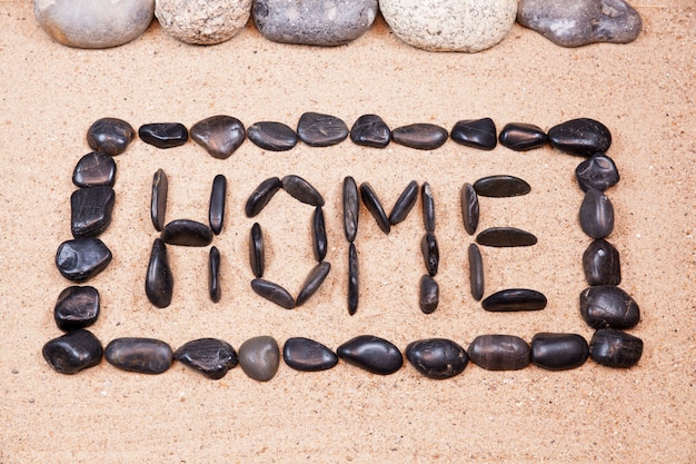 Word home written with pebbles on the sand of a beach