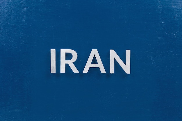 The word iran laid with silver metal letters on classic blue board in flat lay with central composition