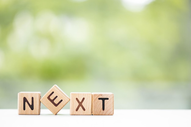 NEXT word is written on wooden cubes on a green summer background Closeup of wooden elements