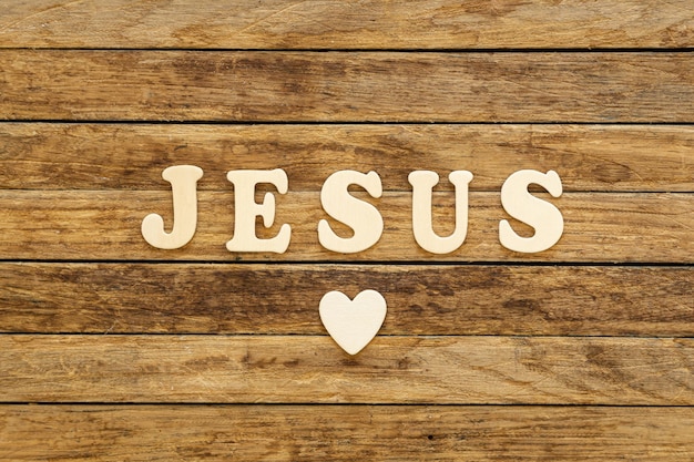 Word Jesus written with wooden letters on wooden background top view