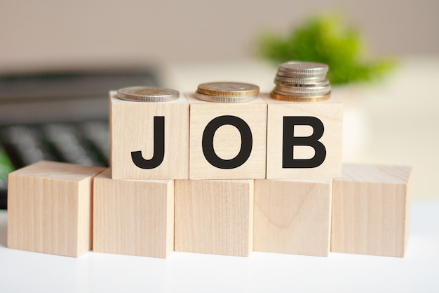 The word job on wood cubes, banknotes and calculator on the background.