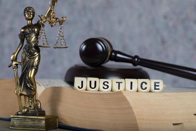 写真 木製の文字で構成された単語 justice。バック グラウンドでテミス像と裁判官の小槌。
