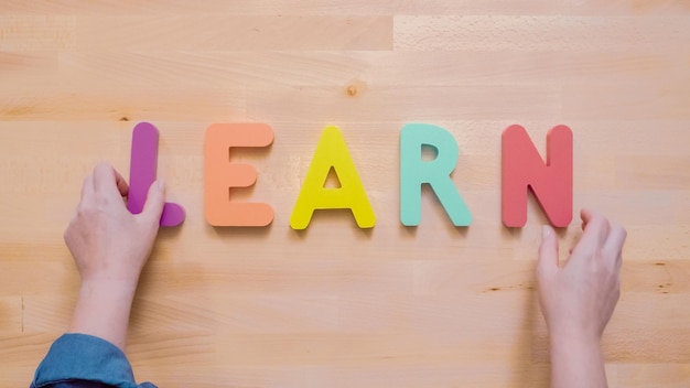 Word LEARN from multicolor wooden letters on wooden table.