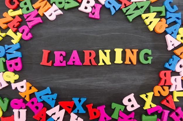 La parola apprendimento disposta in lettere colorate su uno sfondo di legno nero