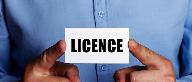 The word LICENCE is written on a white business card in a man's hands. Business concept