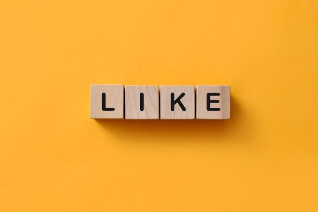 the word like on wooden cubes on a yellow background