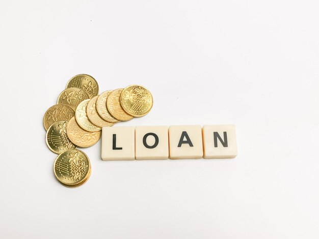 Photo word loan made of square letter tiles with coins against white background.