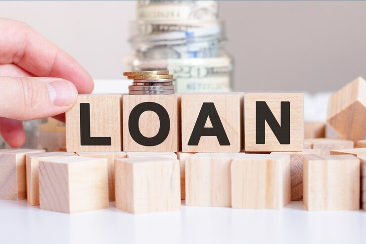 The word Loan on the wooden blocks and a bank with money, business concept