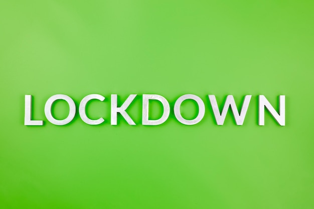 The word lockdown laid with brushed aluminium metal letters on green background