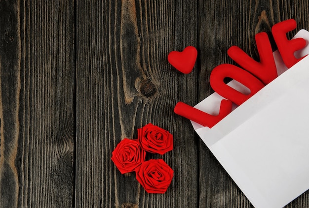 Word LOVE, heart and hand made roses on wooden background. Concept of Valentine's Day.