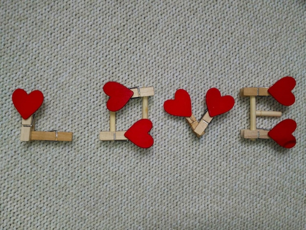 the word love is lined with wooden letters with red hearts. on beige knitted background. Valentine