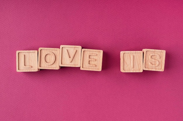 The word love is made up of wooden cubes on a bright pink background flat flat, top view. Love Message. The concept of a greeting card for Valentine's Day, Mother's Day, Women's Day, March 8