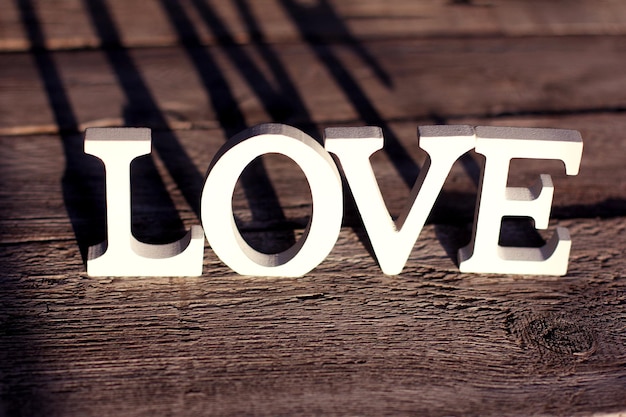 The word LOVE is made of white letters on a brown wooden background. Valentine's Day, love, eco materials