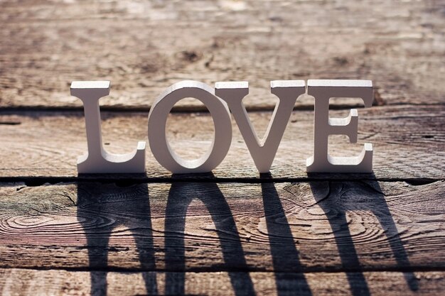 The word love is made of white letters on a brown wooden background valentines day love eco materials person