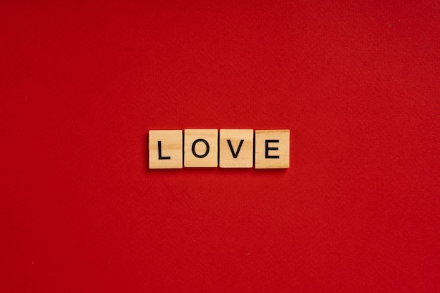 The word LOVE is made of wooden blocks on a red background