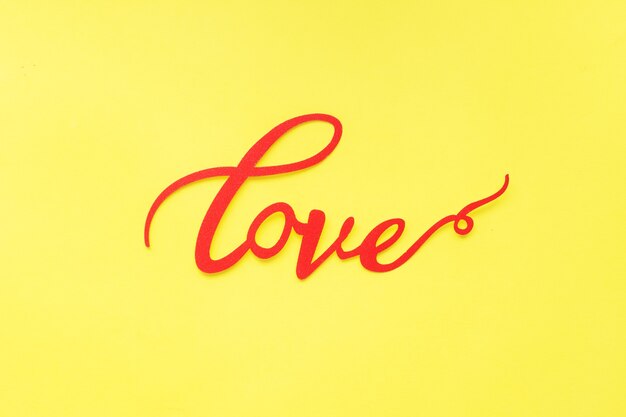 The word Love and red hearts on a yellow background, top view. Holiday card for Valentine's Day. Flat lay.