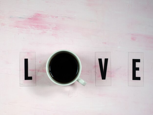 Word LOVE with cup of coffee.