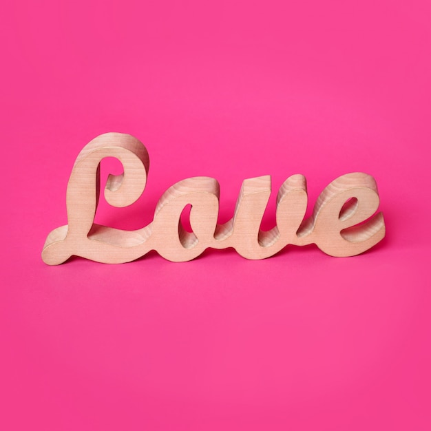 the word love in wooden letters on pink background