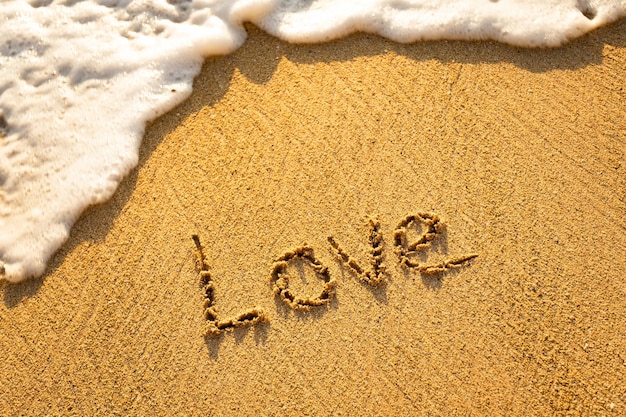 Photo the word love written in the sand on the beach
