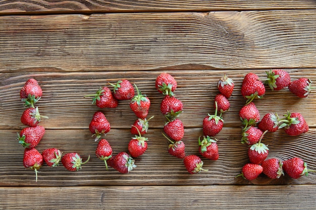 Word love written with strawberries on wooden rustic background. Concept. Top view