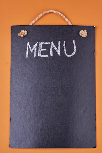 Word MENU written with chalk on black board on color background