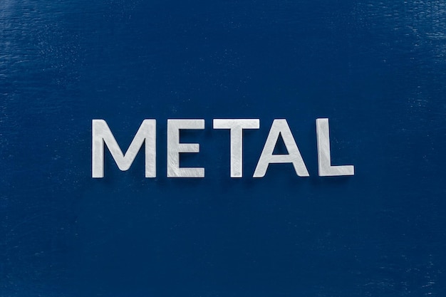 The word metal laid with silver letters on blue color\
surface