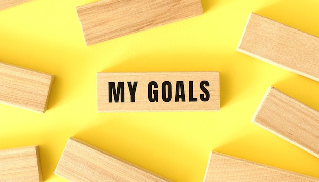 The word my goals is written on a wooden blocks on a yellow background