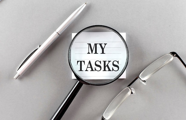 Word MY TASKS on sticky through magnifier on grey background