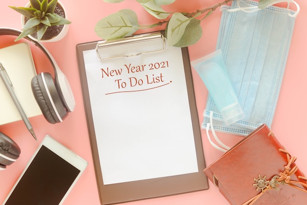 写真 文房具、マスク、手指消毒剤を使用したクリップボードのword new year 2021 todoリスト。 2021年の新年にリストを行うために提示する概念、新しい通常のポストコビッド-19パンデミック。