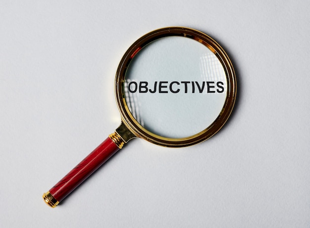 Word objectives through magnifier on blue gary background target concept