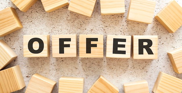 The word OFFER consists of wooden cubes with letters, top view on a light background.