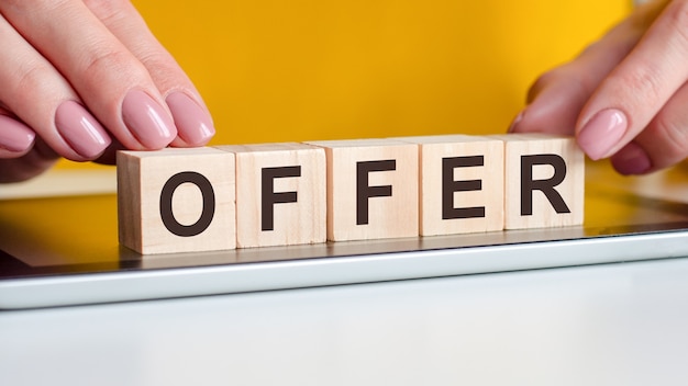 The word offer written on wooden cubes standing on a notepad. selective focus. business, financial concept