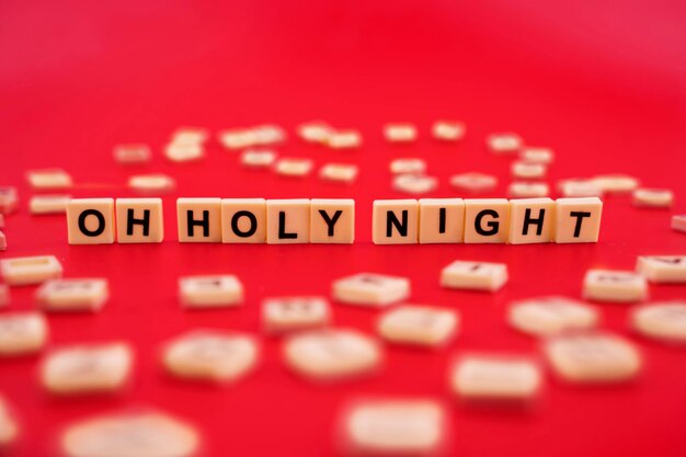 The word OH HOLY NIGHT with wooden letter tiles isolated on red background