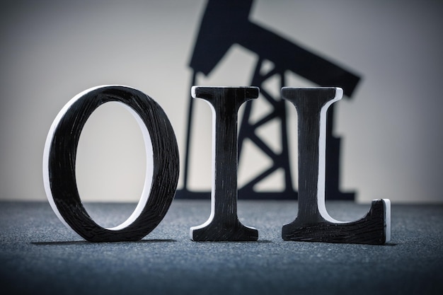 Word OIL with oil pump on dark grey background World Oil Industry concept