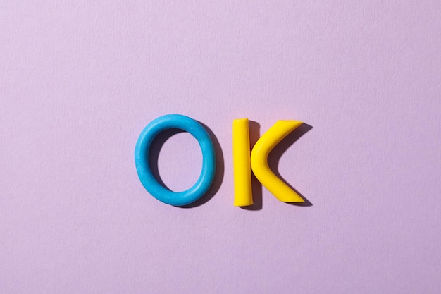 The word ok laid out from colored plasticine on a purple background