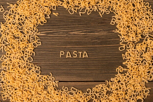 The word "pasta" is laid out of small pasta on a wooden background