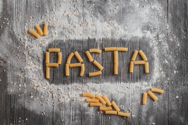 Word pasta,  laid out on an old black wooden desk.