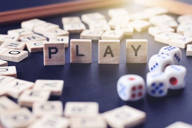 Word PLAY with wooden letters on black Board with dice and letter in the circle