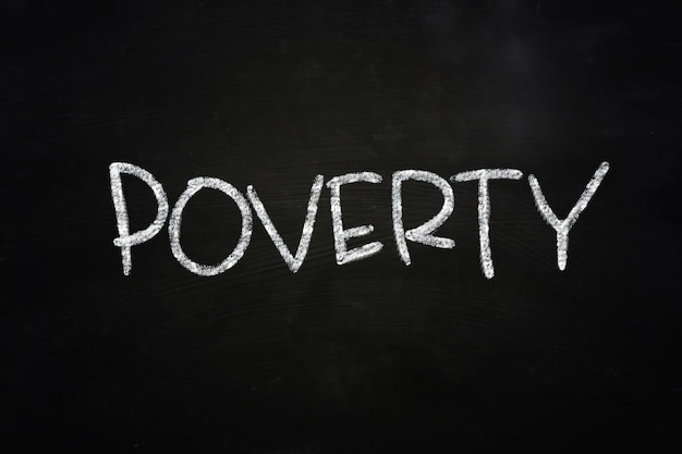 Photo the word poverty written with chalk on blackboard