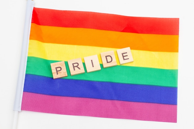 Word PRIDE gemaakt van houten kubussen op een LGBT-trotsvlag.