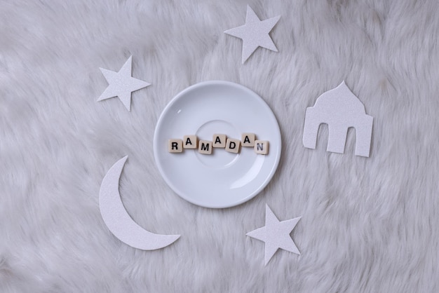 Word ramadan on plate with moon and star isolated on white background.