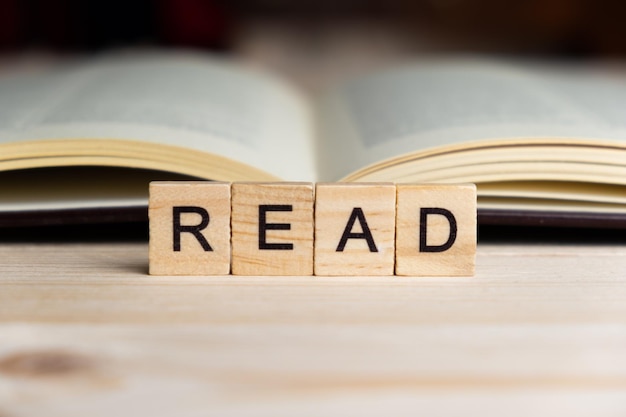 Word READ written with wooden blocks next to books on a table Study and knowledge concept